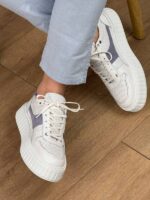 Bele muške kožne patike sa belim pertlama, levi bočni pogled, model u jeans pantalonama