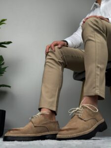 Bočni detalj muške cipele bež boje sa pertlama pored saksije i bež pantalona