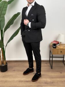 Muško odelo crno sa dvorednim kopčanjem, blagi profil modela uz palmu i lampu u kadru