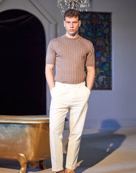 Bež muska old money majica rebrastog pletenja na modelu sa rukama u džepovima krem pantalona