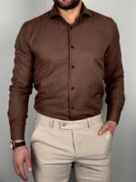 Braon muška košulja zategnuta uz telo sa svetlim pantalonama, profil sa rukom u džepu