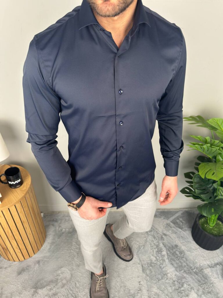 Elegantna muška košulja teget, profilni kadar, ruka u džepu i sivkasti pantalonski kroj