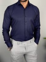 Tamno teget muška košulja zategnuta na grudima sa svetlim pantalonama i kožnim cipelama