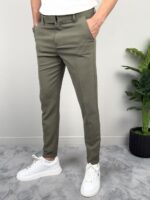 Maslinaste elegantne muške pantalone pun rast modela sa palmom u uglu kadra