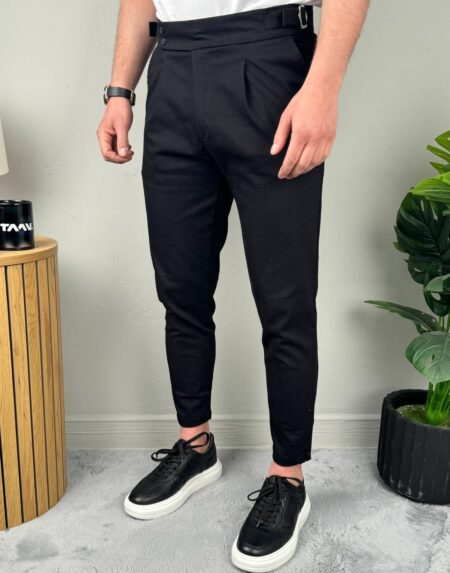 Model u crnim elegantnim muškim pantalonama sa podesivim pojasom, frontalni stav uz beli zid