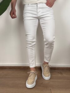 detalj prednje strane muških belih farmerki uz bež patike