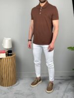 Braon muška polo majica iz poluprofila uz neutralnu zidnu pozadinu
