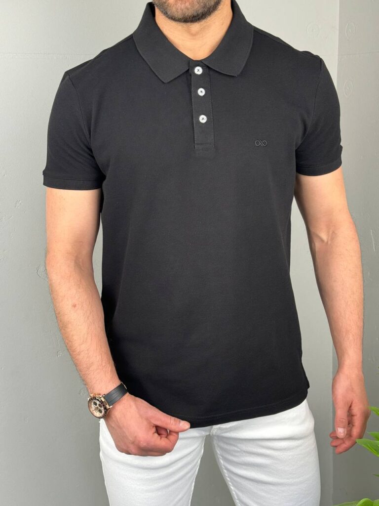 Pamučna muška polo majica u crnoj boji, frontalni prikaz na modelu sa belim pantalonama