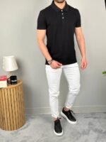Crna polo majica iz blagog poluprofila, model uz svetlu zidnu pozadinu