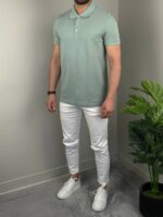 Mint muška polo majica iz blagog ugla, model uz drvenu komodu i biljku