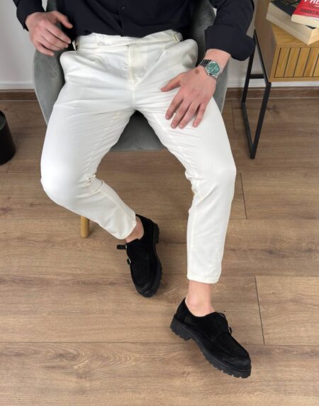 Krem elegantne muške pantalone sa podesivim pojasom, opušten stav modela u enterijeru
