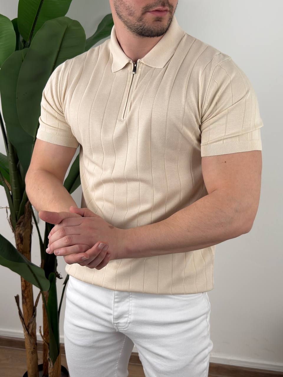 premium-knit-zip-polo-majica-bez-m1007-11-slika-1 Muška bež polo majica sa zipom u krupnom planu sa rukama spojenim ispred tela