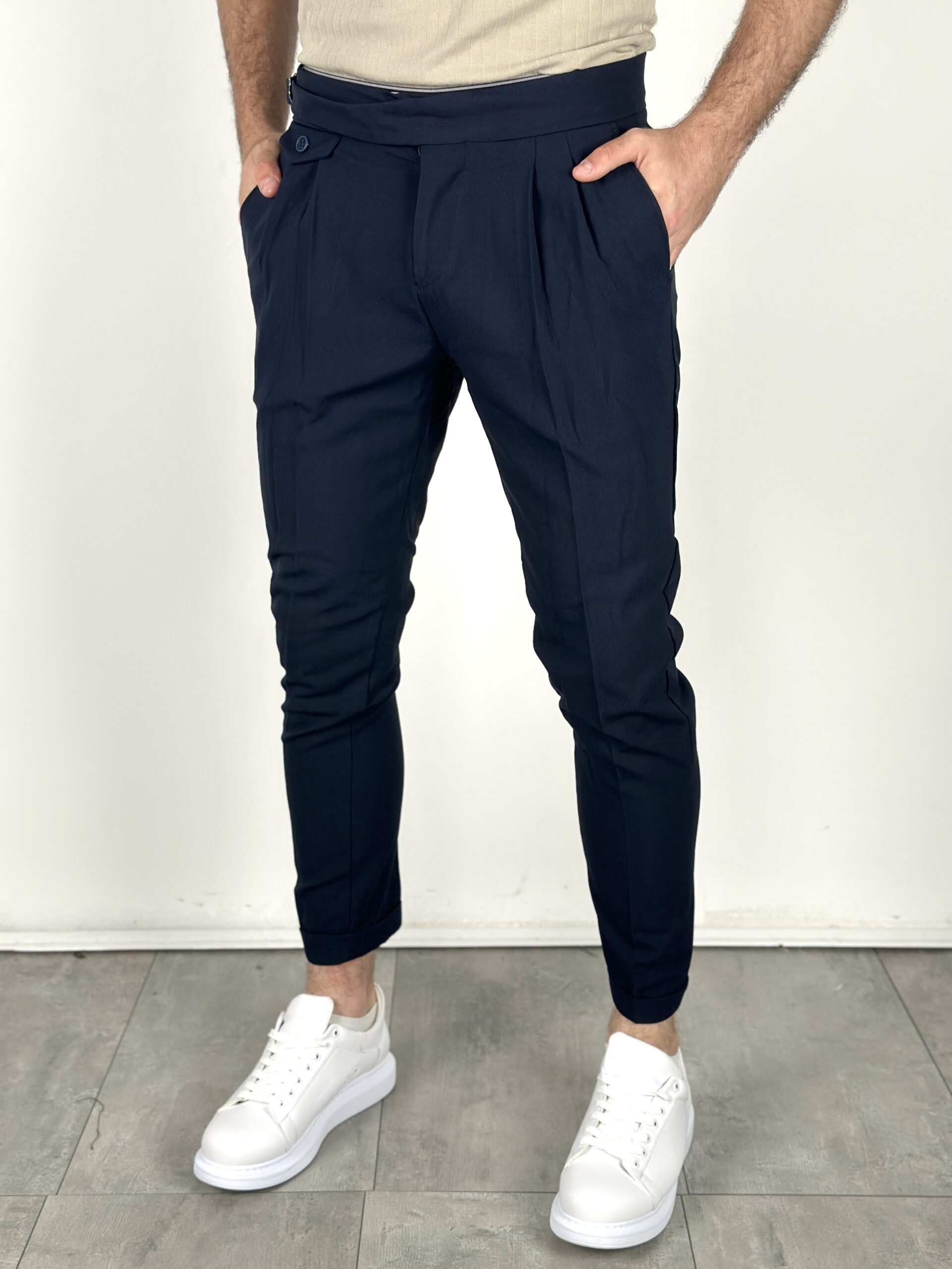 teget-elegantne-pantalone-p3188-09-slika-1-glavna Teget elegantne pantalone sa naborima u struku, prednji kadar, ruke u džepovima i bele patike