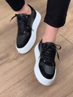 Crne kožne patike C4223 u koraku, bočni profil, vidljive crne pertle i beli šav