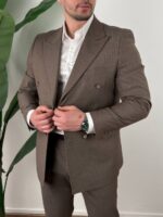 Braon muško odelo na pruge, model sedi opušteno, vidljiv kroj pantalona i sakoa